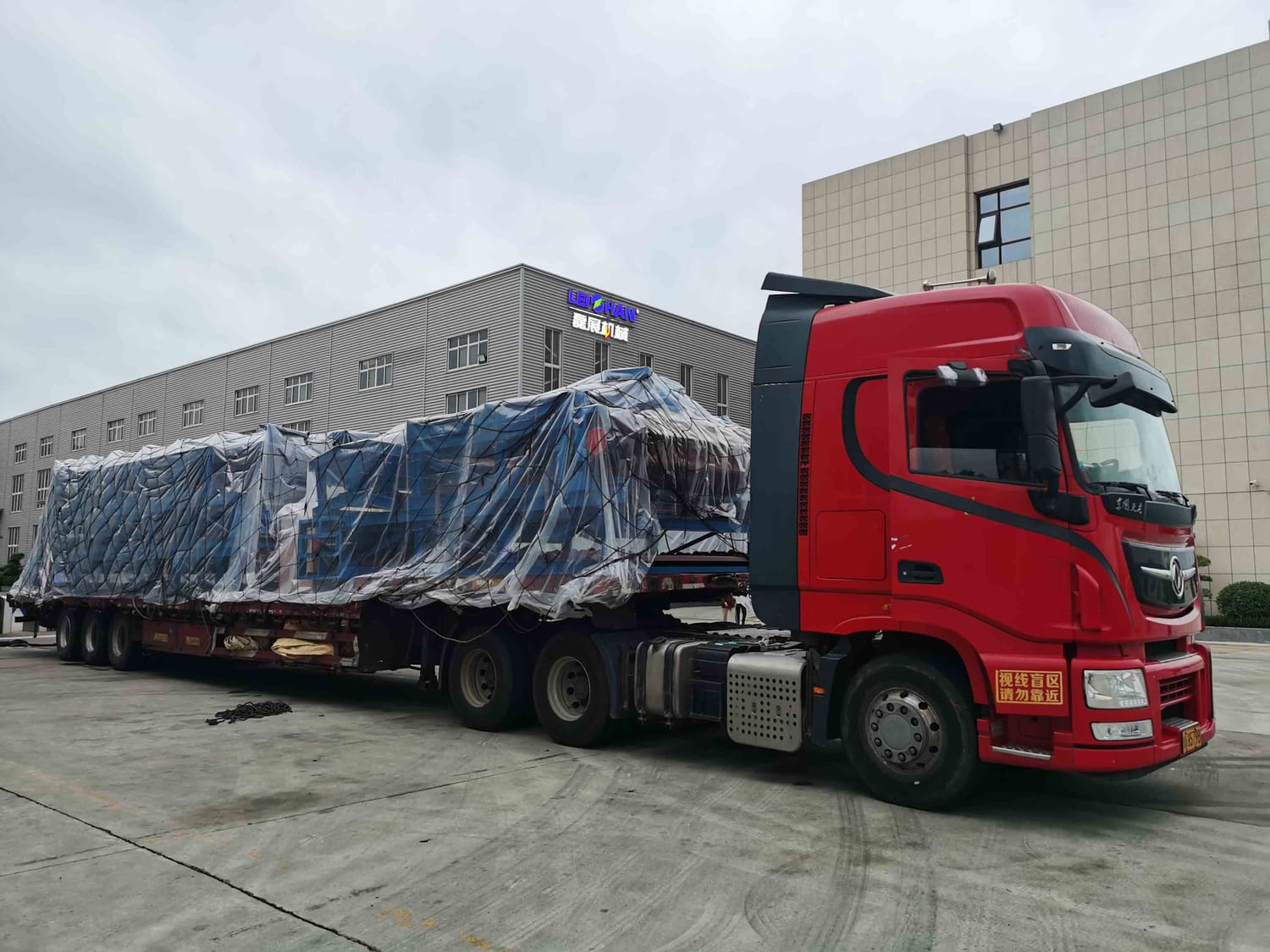 Camion cu semiremorică platformă transportând un utilaj ambalat